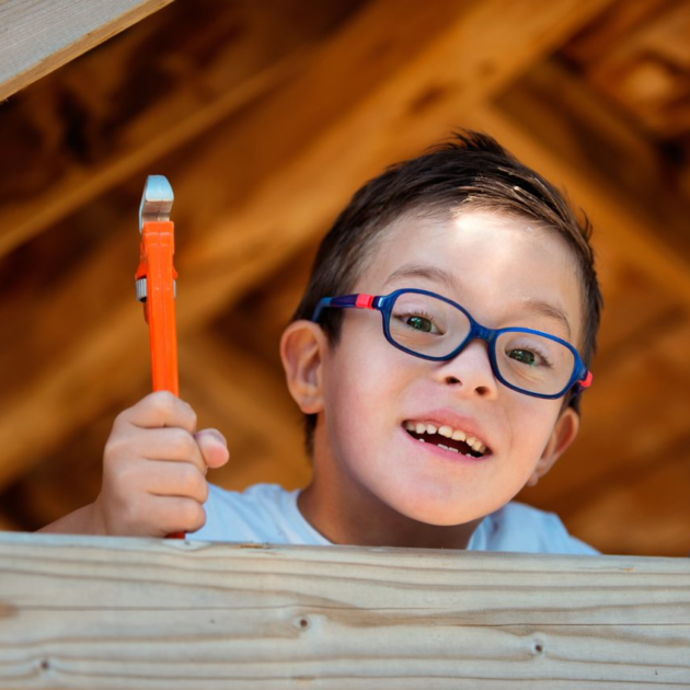 Young boy holding up tools.