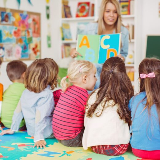 Teacher showing a book of letters to students.